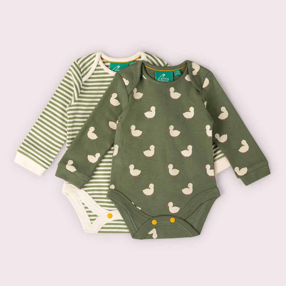 Two long-sleeve baby bodysuits laid flat on a pale pink background. The front bodysuit is olive green with a repeating duck print, and the back bodysuit is white with green stripes.